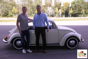 Michael Haberland und Christian Lindner lachen vor einem Käfer in die Kamera