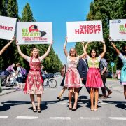 5 Mädchen in Dirndl halten auf einer Straße Schilder in die Luft