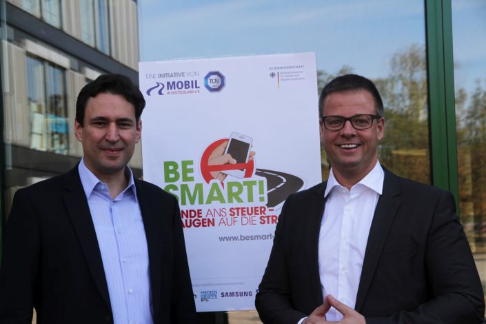 Zwei Herren vor einem BeSmart Plakat