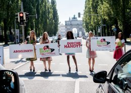 5 Mädchen in Dirndl halten auf einer Straße Schilder in den Händen