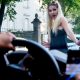Ein Mann mit Handy am Steuer übersieht eine blonde Frau auf der Straße