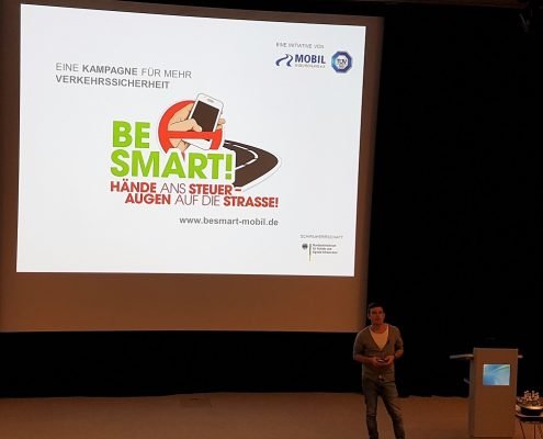 Ein junger Mann steht vor einer großen Leinwand mit BeSmart Präsentation