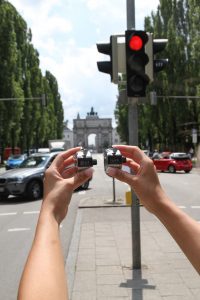 Zwei Hände halten jeweils einen Verkehrszähler, im Hintergrund eine belebte Straße