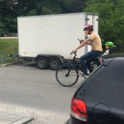 Fahrradfahrer mit Kind im Kindersitz und Handy in der Hand